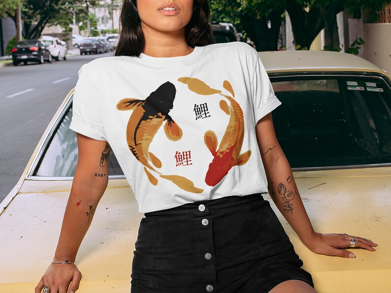 May include: White t-shirt with a graphic of two koi fish swimming in a circle. The fish are black and orange with gold accents. The word "鯉" is written in red on the shirt.