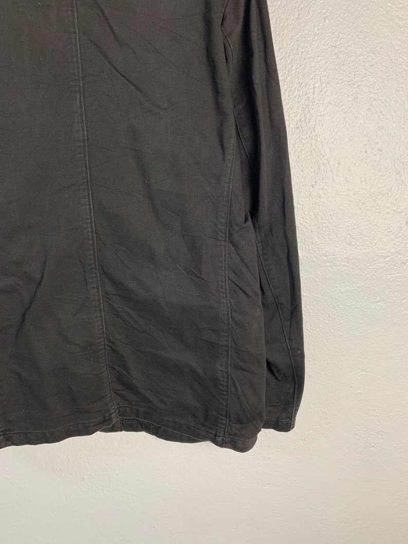 Puede incluir: Chaqueta negra de manga larga con costuras visibles y tejido texturizado. La chaqueta tiene un dise&ntilde;o cl&aacute;sico con un corte entallado. La prenda est&aacute; hecha de un material oscuro y de color s&oacute;lido.