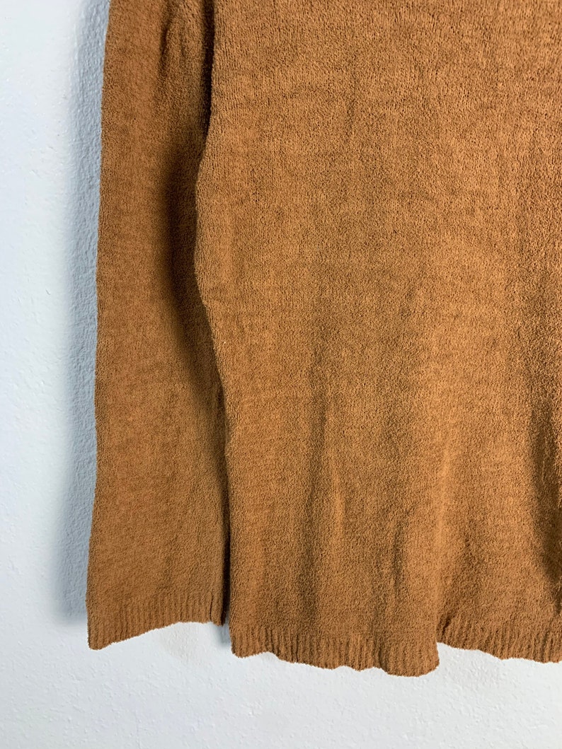 Puede incluir: Un su&eacute;ter marr&oacute;n peludo con mangas largas.