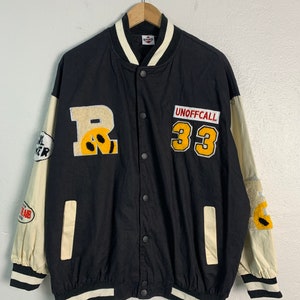 May include: Black baseball jacket with white and yellow trim. The jacket has a large yellow "R" with a smiley face on the left side and a yellow patch with "UNOFFCALL 33" on the right side.