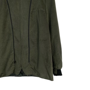 May include: A dark green jacket with a zipper closure and black trim. The jacket has a long sleeve and a relaxed fit.