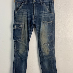 Puede incluir: Pantalón cargo de mezclilla azul desgastado con múltiples bolsillos y un aspecto descolorido.