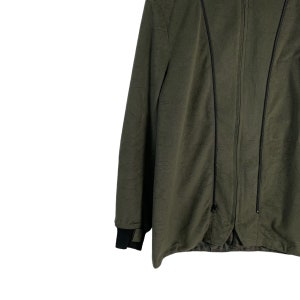 May include: A dark green jacket with a zipper closure and black trim. The jacket has a long sleeve and a relaxed fit.