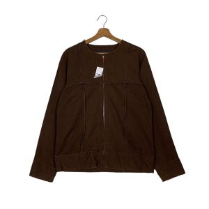 May include: A brown jacket with a full-length zipper and long sleeves. The jacket has visible stitching details and is hanging on a wooden hanger. A price tag is attached to the zipper.