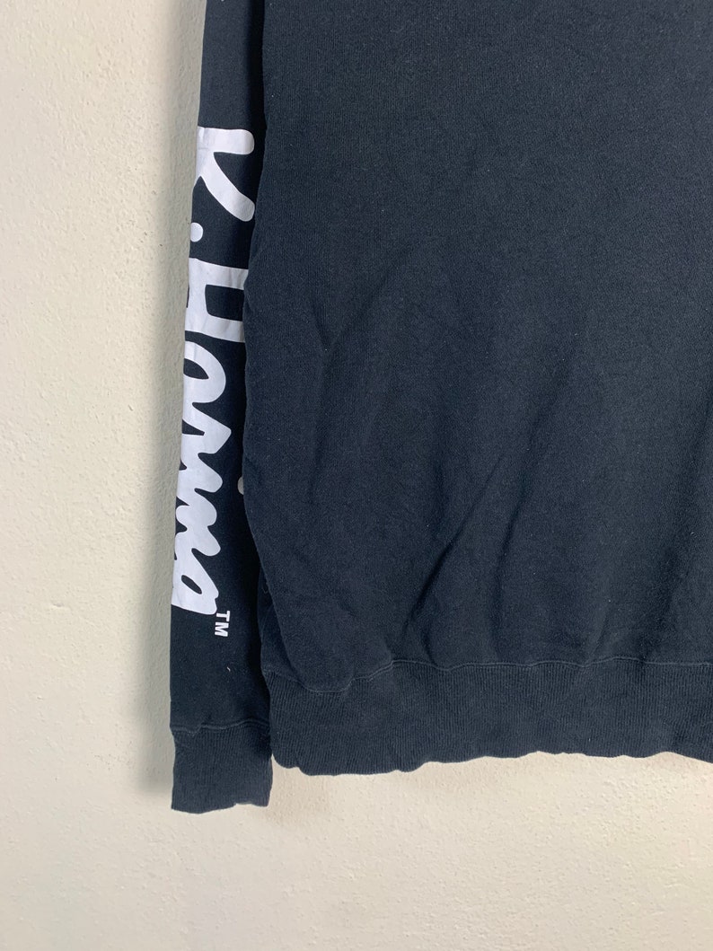 May include: Black long-sleeve sweatshirt with white lettering on the left sleeve that says "K-Swiss" with a trademark symbol.