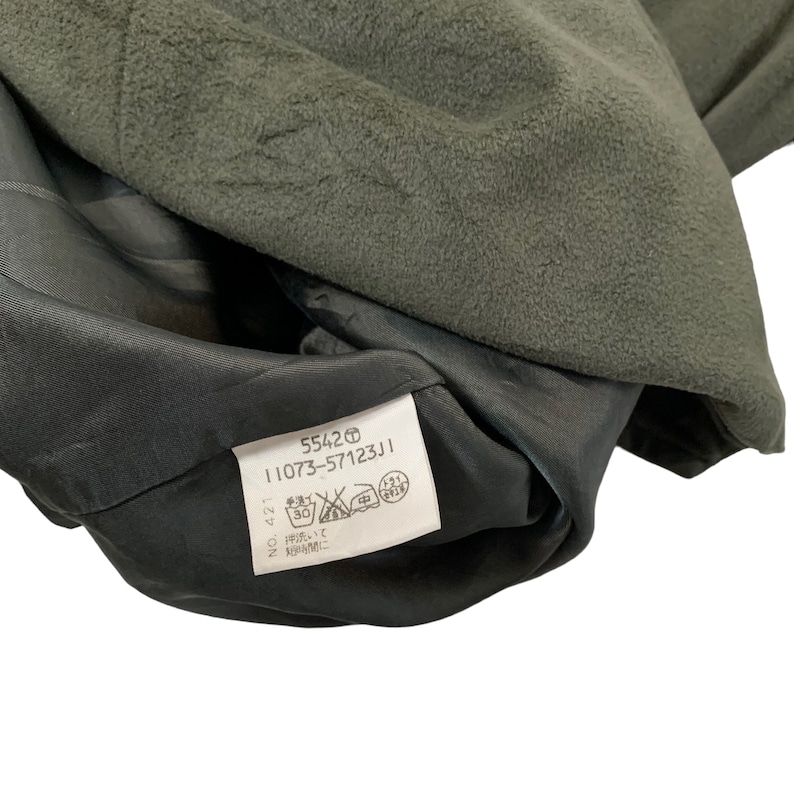 May include: A black and green garment tag with the text "5542 11073-57123J1" and care instructions in Japanese.