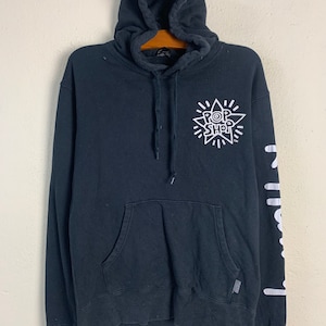 May include: Black hooded sweatshirt with a white graphic of a star with the text "POP SHOP" inside. The right sleeve has a white graphic of the word "POP" repeated vertically.