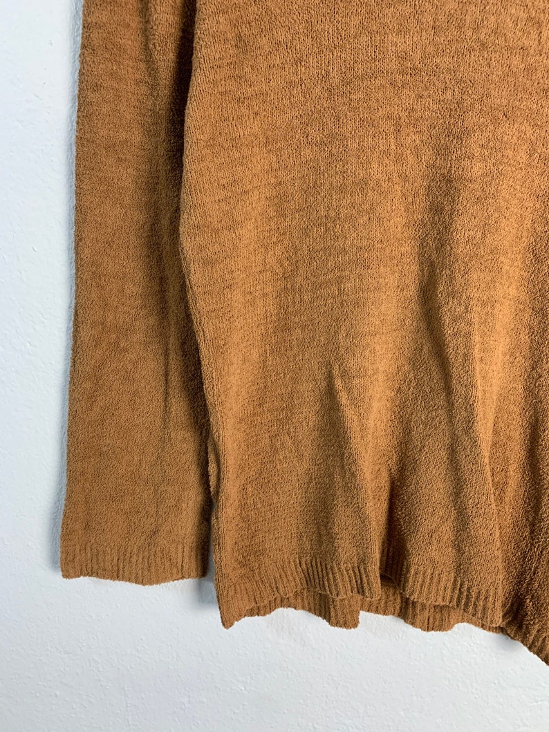 Puede incluir: Un su&eacute;ter marr&oacute;n de manga larga con textura acanalada.