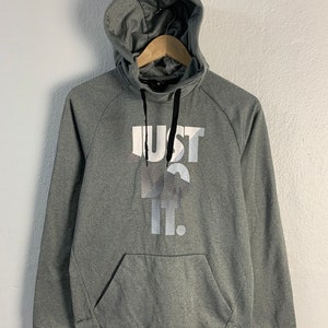 Puede incluir: Sudadera gris con capucha, cordón de ajuste negro y estampado blanco "JUST DO IT." en la parte delantera.