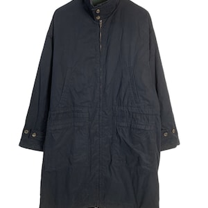 May include: A long, dark blue jacket with a zip closure and multiple pockets. The jacket has a high collar and a button at the neck.