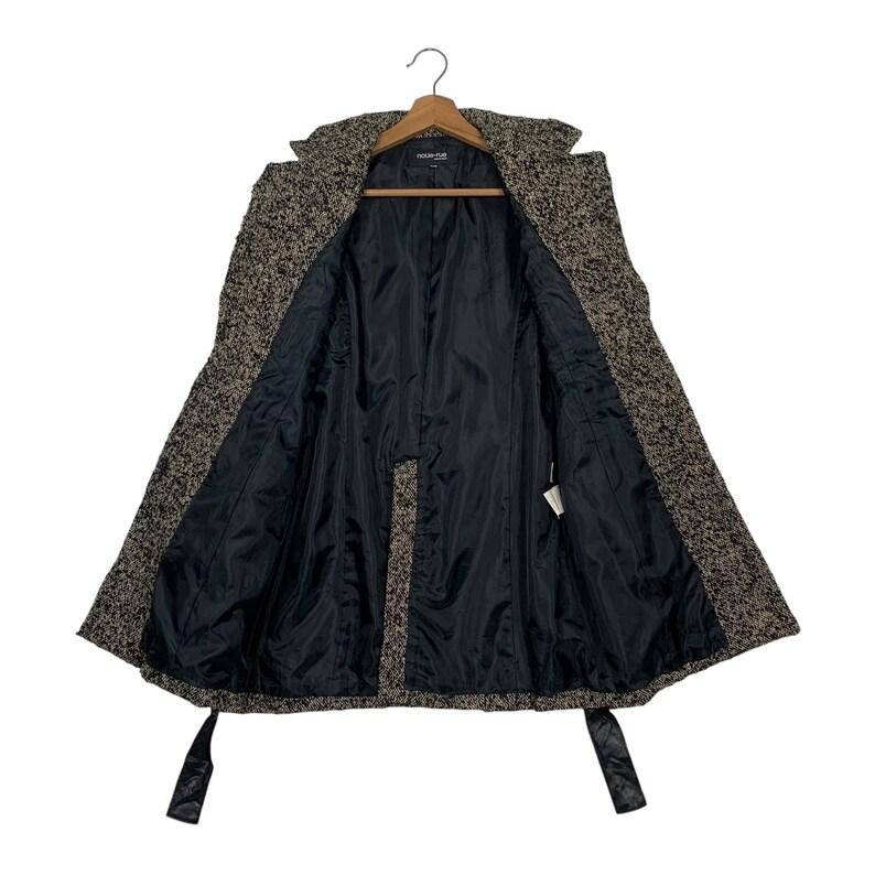 Puede incluir: Abrigo de tweed abierto con forro negro. El abrigo est&aacute; colgado de una percha de madera. Tiene cuello con solapas, mangas largas y cintur&oacute;n anudado. La tela exterior es una mezcla de hilos negros, marrones y blancos.