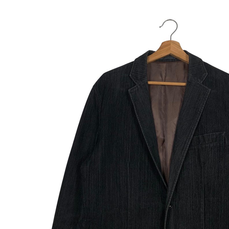 May include: A black corduroy blazer with a striped pattern. The blazer has a single button closure and a pocket on the left side.