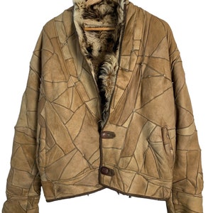 Puede incluir: Una chaqueta de cuero marrón con un diseño de patchwork. La chaqueta tiene un forro de piel y un cierre de botón único.
