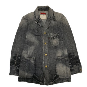 May include: A dark gray denim jacket with a button-up front and multiple pockets. The jacket has a distressed look and features gold-colored buttons.