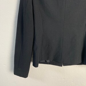 May include: A black blazer with long sleeves and a single button closure. The blazer is made of a smooth, woven fabric.