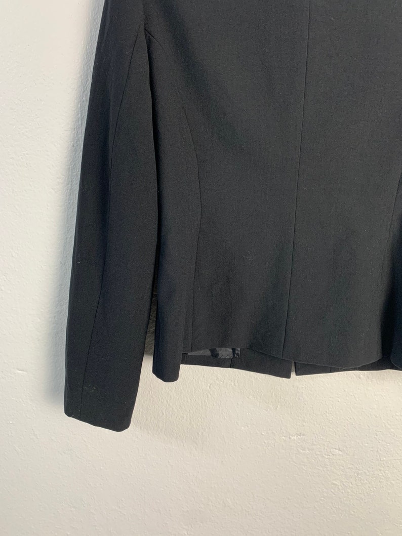 May include: A black blazer with long sleeves and a single button closure. The blazer is made of a smooth, woven fabric.