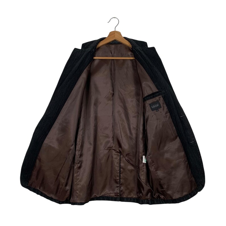 May include: A black corduroy blazer with a brown lining. The blazer has a single button closure and two pockets on the front.