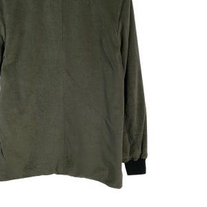 May include: A dark green long-sleeved jacket with a black ribbed cuff. The jacket is made of a soft, textured fabric.