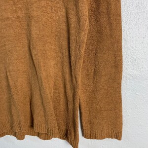 Puede incluir: Un su&eacute;ter marr&oacute;n peludo con mangas largas.