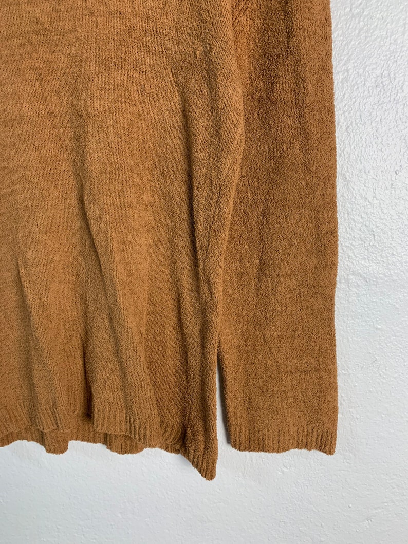 Puede incluir: Un su&eacute;ter marr&oacute;n peludo con mangas largas.