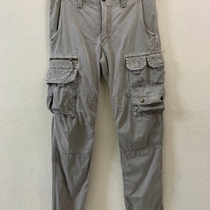 May include: Gray cargo pants with multiple pockets and drawstring closures at the bottom of the legs.