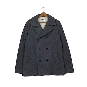 Puede incluir: Un abrigo gris de paño doble botonadura con cierre de botones negros y dos bolsillos delanteros. El abrigo tiene una etiqueta que dice "GDC".