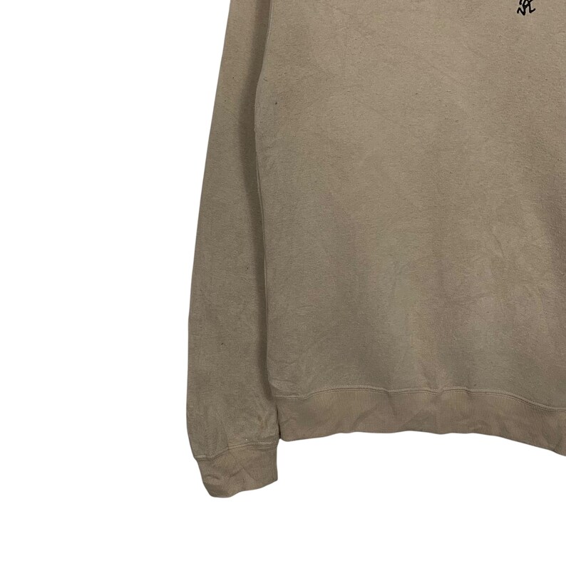 May include: A light brown sweatshirt with long sleeves. The sweatshirt has a ribbed hem and cuffs.