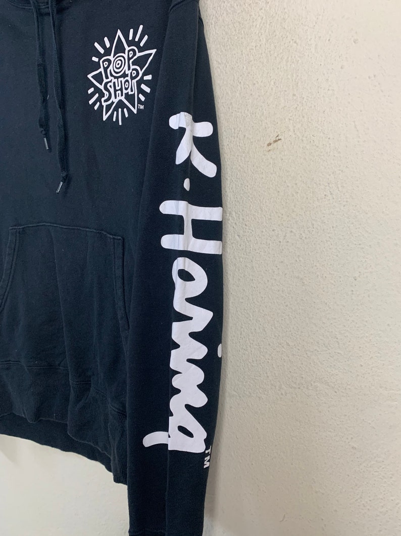 May include: Black hooded sweatshirt with a white graphic of a star with the text "Pop Shop" inside. The right sleeve has the text "K-Harma" in white.