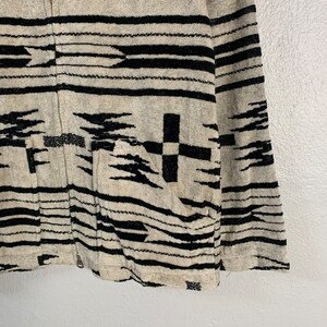 Puede incluir: Una chaqueta con estampado en blanco y negro con cierre de cremallera. La chaqueta tiene un dise&ntilde;o geom&eacute;trico de estilo suroeste.