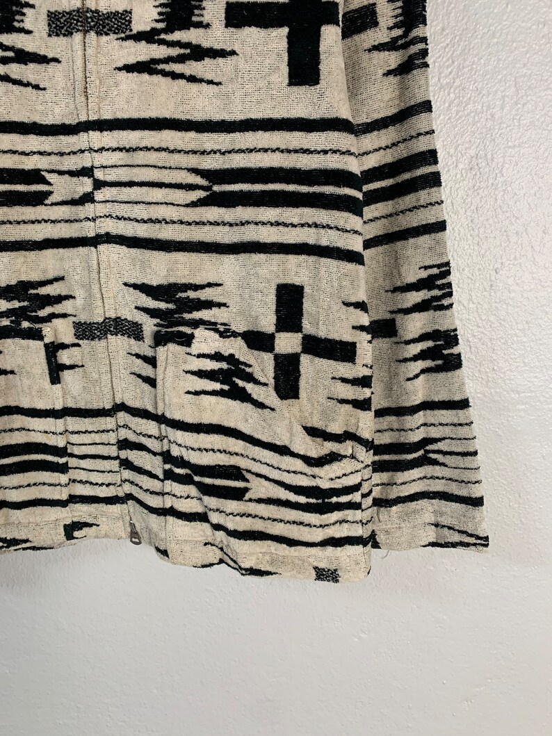 Puede incluir: Una chaqueta con estampado en blanco y negro con cierre de cremallera. La chaqueta tiene un dise&ntilde;o geom&eacute;trico de estilo suroeste.