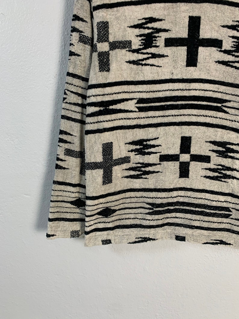 Puede incluir: Tejido tejido en blanco y negro con un patr&oacute;n geom&eacute;trico que presenta cruces y zigzags.