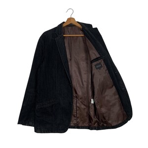 May include: A black corduroy blazer with a brown satin lining. The blazer has a single button closure and two pockets on the front.