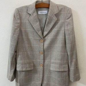 May include: A gray plaid blazer with a brown label that says "MaxMara" on the front. The blazer has a notched collar, three buttons, and two pockets.
