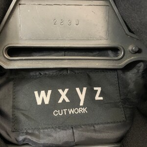 May include: Black label with white text that reads "WXYZ CUT WORK" and the number "2830" on a black hanger.