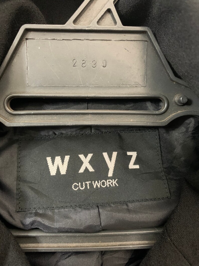 May include: Black label with white text that reads "WXYZ CUT WORK" and the number "2830" on a black hanger.