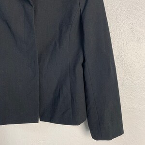 May include: A black blazer with a long sleeve and a single button closure.