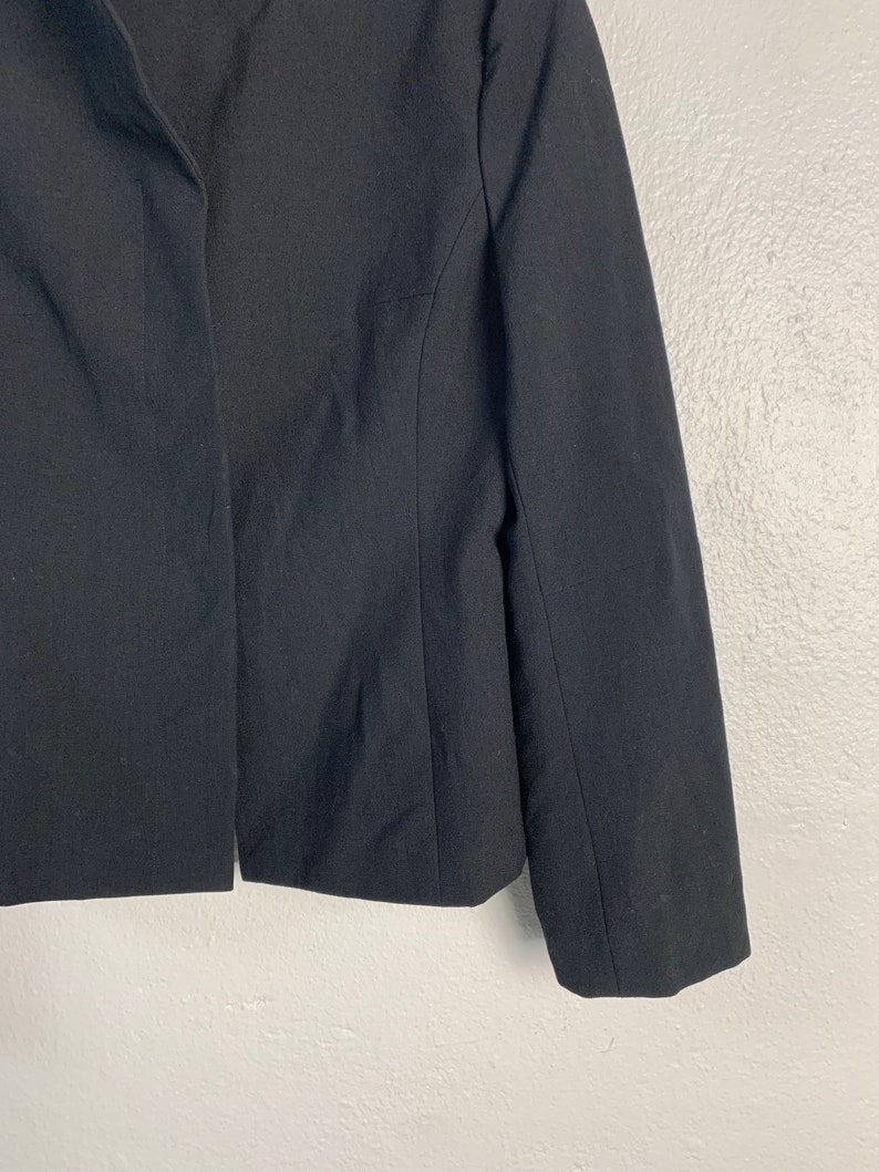 May include: A black blazer with a long sleeve and a single button closure.