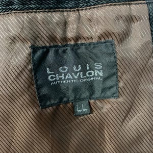 May include: A black label with white text that reads "LOUIS CHAVLON AUTHENTIC ORIGINAL". The label is attached to a brown fabric with a striped pattern.