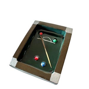 Könnte beinhalten: Ein rechteckiges Tablett mit dunkelbraunem Rahmen und silbernen Eckakzenten sowie einer glänzenden dunkelgrünen Innenfläche. Das Tablett zeigt ein Miniatur-Billardtisch-Design mit drei kleinen Billardkugeln und einem dünnen Queue.