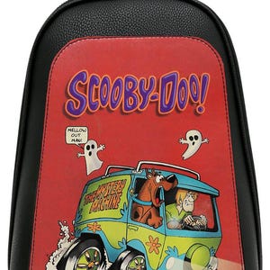May include: A black backpack with a red front panel featuring a Scooby-Doo graphic. The design shows the Mystery Machine van with Scooby-Doo and Shaggy inside, two ghosts, and the text "SCOOBY-DOO!" and "MELLOW OUT MAN!" printed on the red background.