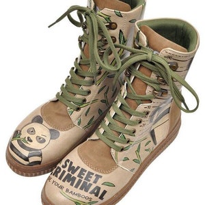 May include: A pair of tan ankle boots with green laces. The boots have a panda bear graphic on one boot and the text "Sweet Criminal Be Your Bamboos" on the other.