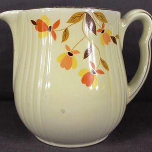 May include: A white ceramic mug with a black handle and the text "But First, Coffee" in a handwritten style. The mug is on a white surface. The mug is 4 inches tall.