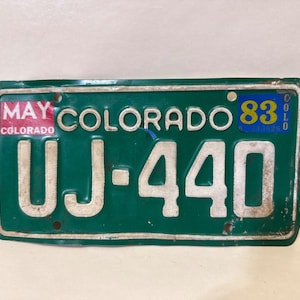 Puede incluir: Una placa de matrícula vintage de Colorado, verde con letras blancas. La placa muestra "COLORADO" en la parte superior y "UJ-440" en el centro. La placa también tiene una pegatina "MAY COLORADO" y una pegatina "83".