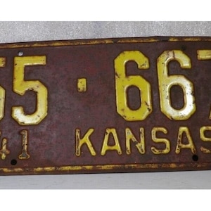 May include: Vintage Kansas license plate with yellow numbers and lettering on a brown background. The plate reads "55-667" and "KANSAS" with the year "41" at the bottom. The plate shows signs of age and wear.