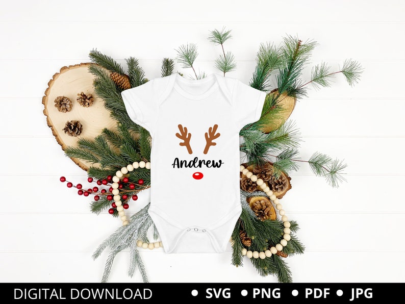May include: White onesie with a brown reindeer face and red nose. The onesie has the name "Andrew" printed on it.