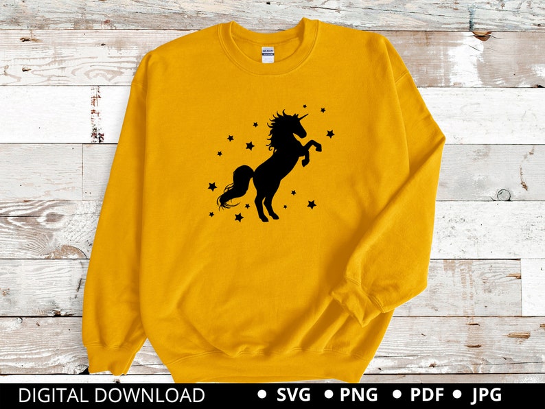 Puede incluir: Una sudadera amarilla con una silueta negra de un unicornio con un dise&ntilde;o de estrellas.