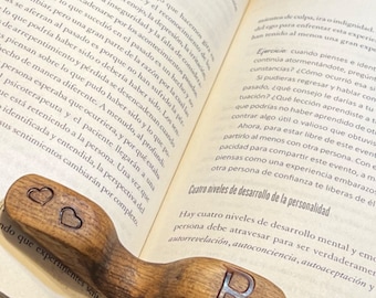 May include: A wooden bookmark with a carved heart and the letter "R" on a book with text about therapy. The book is open to a page with the title "Four Levels of Development of the Personality".