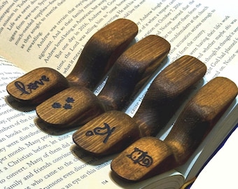 May include: Set of six wooden bookends with different engraved designs, including "love", a bird, a clover, and a heart. The bookends are dark brown and have a natural wood finish.