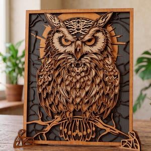 Op de afbeelding: Een gelaagd houten kunstwerk van een uil. De uil is ingewikkeld uit hout gesneden en toont gedetailleerde veren en gelaatstrekken. Het kunstwerk is geplaatst tegen een donkergrijze achtergrond met een lichtbruine zon en boomtakken.