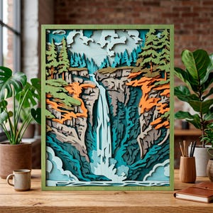 Könnte beinhalten: Ein mehrschichtiges Holzkunstwerk, das eine Wasserfallszene darstellt. Das Kunstwerk hat einen grünen Rahmen und verwendet verschiedene Blau-, Grün-, Orange- und Brauntöne, um Tiefe zu erzeugen. Der Wasserfall stürzt einen Felsen hinunter, umgeben von Bäumen und Blättern.